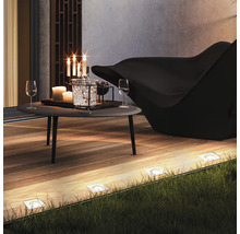 Terrassenszene mit Tisch, Stuhl, Bodenleuchten und Dekoration für den Außenbereich