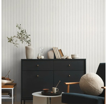 Modernes Wohnzimmer mit Paneelwand, Kommode, Sessel und dekorativen Elementen für ein stilvolles Ambiente.