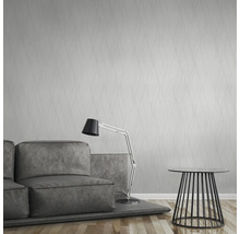 Helles Zimmer mit Tapete mit Wellenmuster, Sofa, Stehlampe und Beistelltisch.