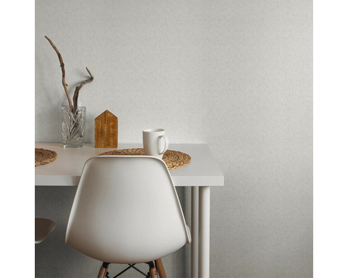 Szene mit strukturierten Tapeten an der Wand, einem Tisch, einem Stuhl, einem Glas, einem Holzhaus und einer Tasse