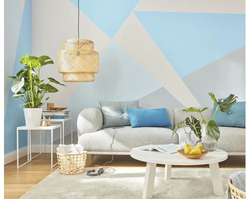 Wohnzimmer mit Sofa, Tisch, Pflanzen und geometrischer Wandgestaltung