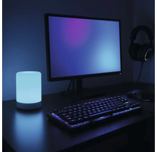 Szene mit Computermonitor, Tastatur, Maus, Kopfhörern und Tischleuchte