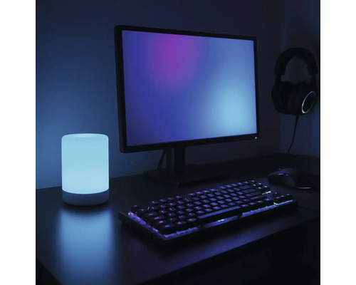 Szene mit Computermonitor, Tastatur, Maus, Kopfhörern und Tischleuchte