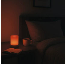 Nachttisch mit Lampe, Buch und Tasse in einem Schlafzimmer.