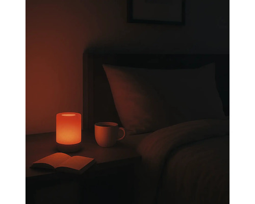 Nachttisch mit Lampe, Buch und Tasse in einem Schlafzimmer.