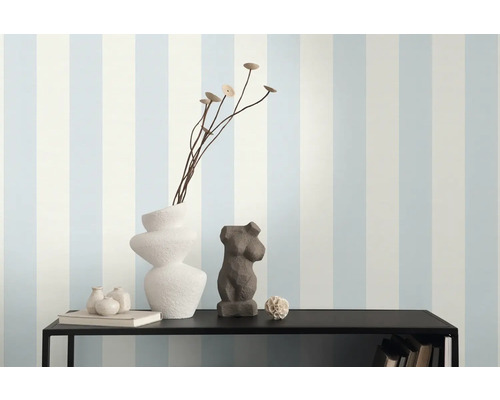 Dekoratives Arrangement auf einem Regal vor einer gestreiften Tapete