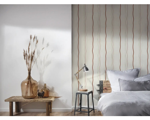 Dekoratives Schlafzimmer mit gemusterter Tapete, Tischlampe und Glasvasen