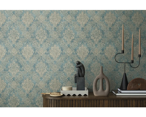 Dekoratives Interieur mit gemusterter Tapete, Skulptur, Kerzenständer und dekorativen Elementen auf einem Holzschrank.