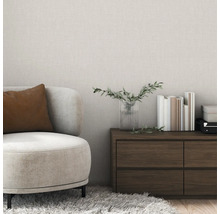 Wohnzimmer mit Sessel, Kommode, Vase und Büchern vor einer strukturierten Tapete