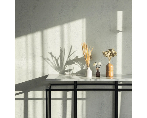 Wand mit Muster, Tisch mit Dekoration wie Vasen und Trockenblumen.
