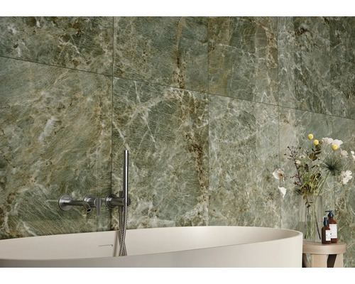 Badezimmer mit grünen Marmorfliesen, Badewanne und Armaturen.