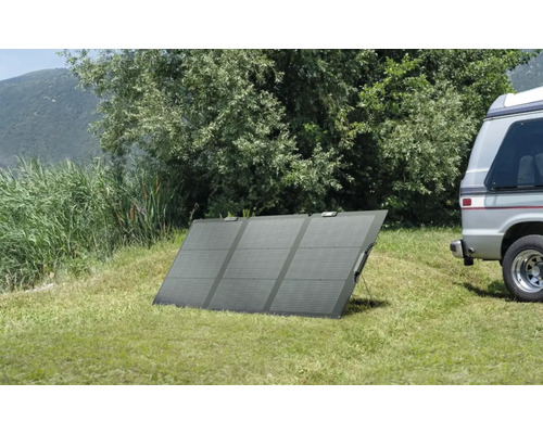 Tragbares Solarmodul auf einer Wiese neben einem Wohnmobil