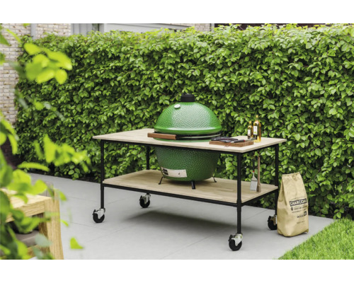Grüner Grill auf einem Tisch mit Rädern, Holzkohle Sack im Garten.