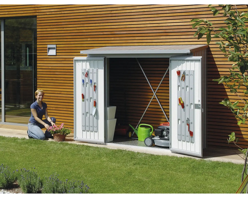 Gartenschrank mit geöffneten Türen, ausgestattet mit Gartengeräten, Rasenmäher und Gießkanne im Garten.