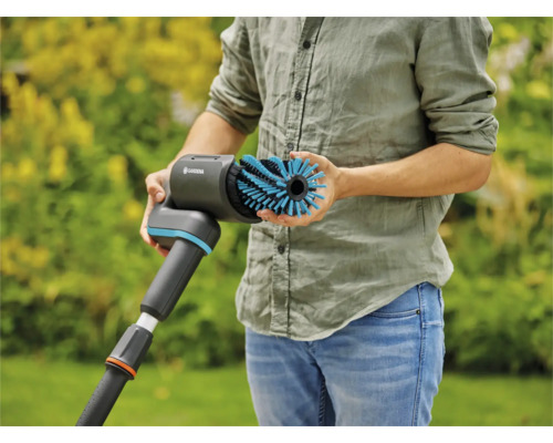 Eine Person hält eine Gardena Bürste zur Reinigung von Oberflächen im Außenbereich