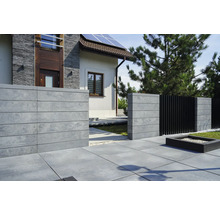 Außenansicht eines Hauses mit Betonzaun und Steinplattenweg