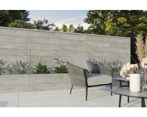 Gartenbereich mit Betonmauer, bepflanztem Beet und Sitzgelegenheit