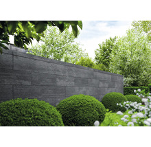 Gartenansicht mit Mauer aus Steinpaneelen und grünen Büschen