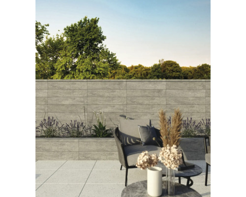 Terrasse mit grauer Steinmauer, Bepflanzung und Sitzgelegenheit