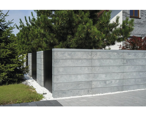 Betonzaun mit Metallelementen und Zierkies im Garten