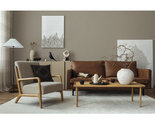 Wohnzimmer mit Ledersofa, Sessel, Holztisch und dekorativen Elementen für eine stilvolle Einrichtung