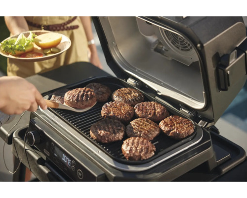 Ein Grill mit mehreren Burger-Patties, die auf dem Grill zubereitet werden.