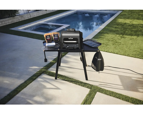 Ninja Woodfire Elektrogrill mit Zubehör auf einem Tisch im Freien