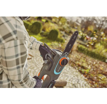 Eine Person bedient eine Gardena Akku-Kettensäge im Garten.