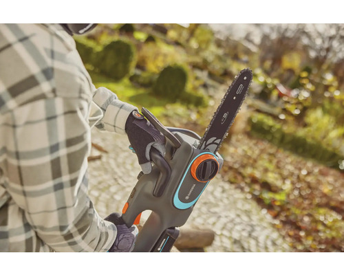 Eine Person bedient eine Gardena Akku-Kettensäge im Garten.