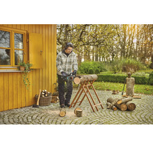 Mann sägt Holz mit einer Kettensäge im Garten.
