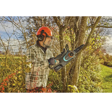 Mann mit Schutzhelm und Gardena Akku-Kettensäge beim Beschneiden eines Baumes.
