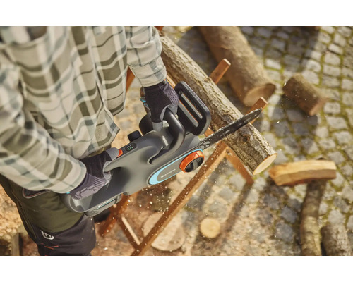 Mann sägt Holz mit einer Akku-Kettensäge von Gardena.