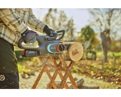 Akku-Kettensäge im Einsatz beim Sägen eines Holzscheits auf einem Holzbock