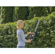 Frau schneidet Hecke mit Akku-Heckenschere