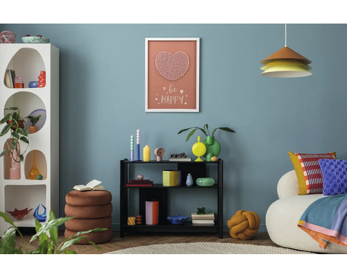 Wohnzimmer mit weißem Regal, schwarzem Regal, Sitzhocker und dekorativen Elementen an der Wand