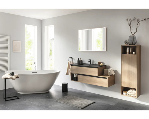 Badezimmer mit Badewanne, Waschtisch, Spiegel und Hochschrank für ein helles und freundliches Ambiente.