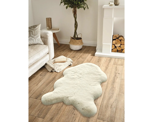 Wohnzimmer mit Sofa, Kamin, Zimmerpflanze und einem Teppich in Felloptik