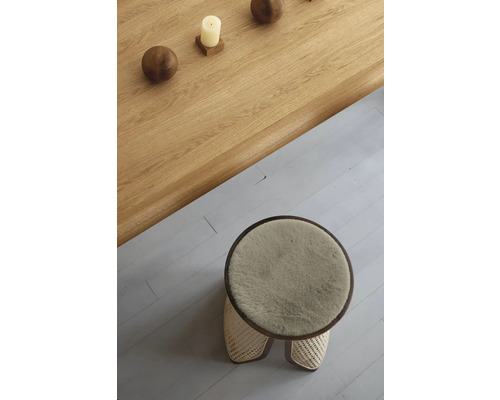Ansicht von oben auf einen runden Hocker mit Fellbezug und einem Holztisch mit Dekoration