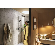 Badezimmer mit Dusche, Sitzbereich und einer Frau unter der Dusche.