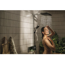 Frau unter einer Duschgarnitur mit Kopf- und Handbrause im Badezimmer mit senkrechten Wandfliesen