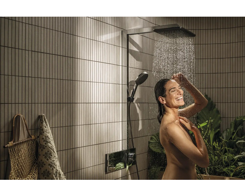 Frau unter einer Duschgarnitur mit Kopf- und Handbrause im Badezimmer mit senkrechten Wandfliesen