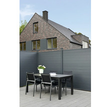 Gartenszene mit Tisch, Stühlen und Zaun vor einem Wohnhaus.