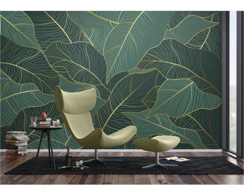 Wohnzimmer mit Blattmuster-Tapete in Grün und Gold, Sessel mit Hocker, Teppich und Beistelltisch mit Dekoration