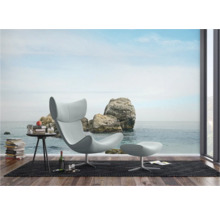 Wohnraum mit Sessel, Hocker und Fototapete mit Felsen am Meer