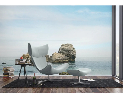 Wohnraum mit Sessel, Hocker und Fototapete mit Felsen am Meer