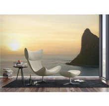 Wohnzimmer mit Sessel, Fußhocker und Fototapete mit Meeresmotiv
