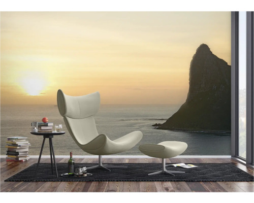 Wohnzimmer mit Sessel, Fußhocker und Fototapete mit Meeresmotiv