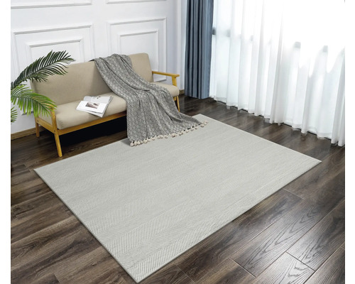 Wohnzimmer mit Sofa und Teppich mit Fischgrätenmuster auf Holzboden