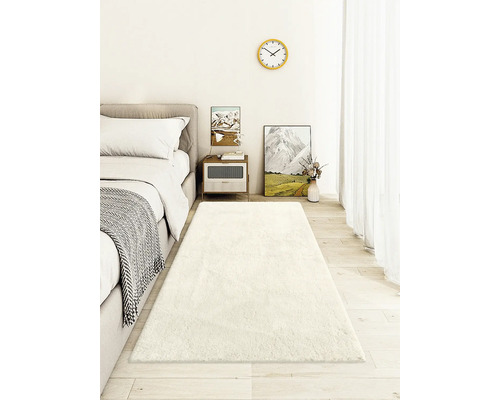 Schlafzimmer mit Bett, Nachttisch und langem, weichen Teppich