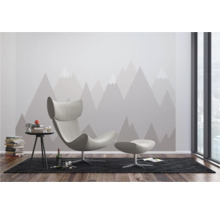 Modernes Wohnzimmer mit Sessel, Hocker, Beistelltisch und Bergmotiv-Tapete.